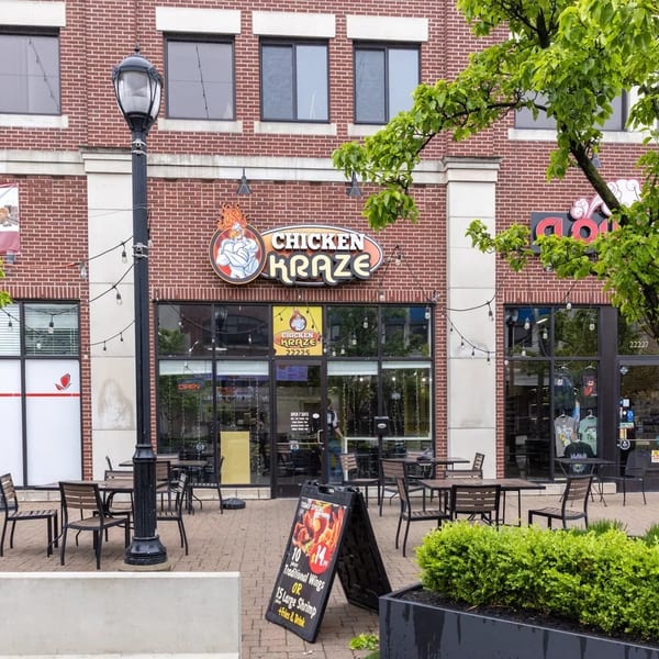 Chicken Kraze restaurant exterior with outdoor seating, brick facade, and a promotional sign for wings and shrimp.