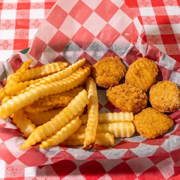 Basket of golden-brown crinkle-cut fries and chicken nuggets on a red and white checkered tablecloth.